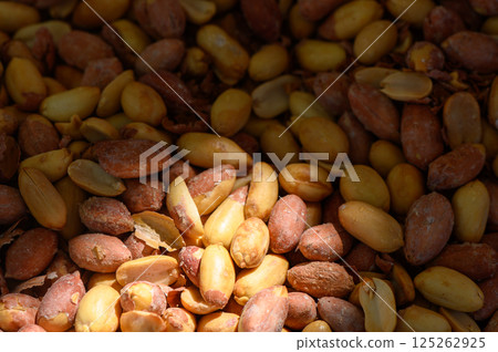 Vibrant assortment of raw peanuts nestled together under soft sunlight in a natural setting 125262925