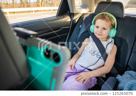 Little girl with tablet and headphones in the car during travel on vacation. Entertainment in the transport for child 125263070