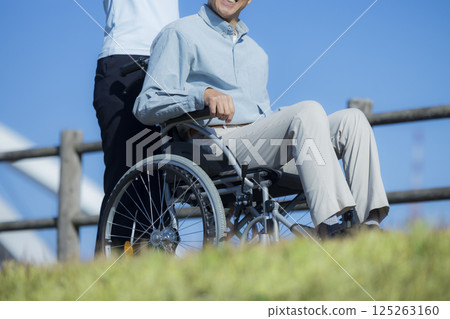 Senior male riding a wheelchair and a caregiver 125263160