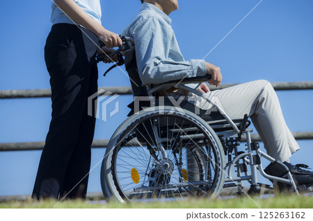 Senior male riding a wheelchair and a caregiver 125263162