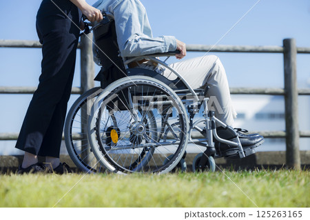 Senior male riding a wheelchair and a caregiver 125263165