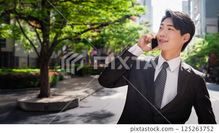 Portrait of a young man in a striped suit making a phone call on a city street 125263752