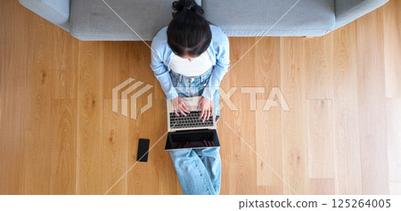 Top view of young Asian woman sitting on the floor and working on computer laptop 125264005