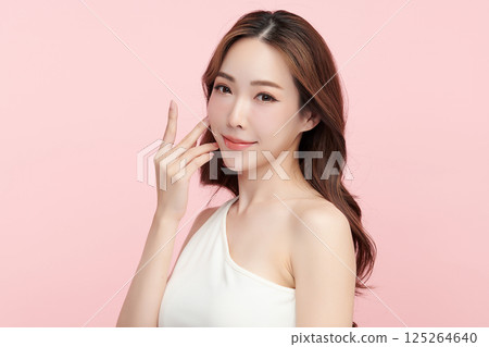 A beautiful young Asian woman with clean, fresh skin against a pink background. Skincare, facial treatment, cosmetology, beauty, and spa. An elegant portrait of an Asian woman. 125264640