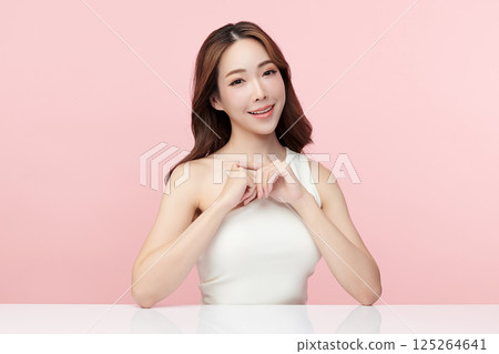 A beautiful young Asian woman with clean, fresh skin against a pink background. Skincare, facial treatment, cosmetology, beauty, and spa. An elegant portrait of an Asian woman. 125264641