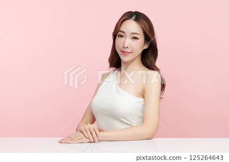 A beautiful young Asian woman with clean, fresh skin against a pink background. Skincare, facial treatment, cosmetology, beauty, and spa. An elegant portrait of an Asian woman. 125264643