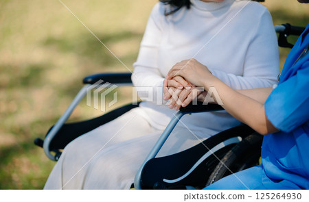 Elderly asian senior woman on wheelchair with Asian careful caregiver. Nursing home hospital garden 125264930