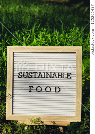 Letter board with text SUSTAINABLE FOOD on background of garden bed with green herb dill. Organic farming, produce local vegetables concept. Supporting local farmers 125265457