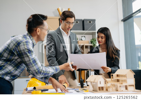 Engineer teams meeting working together wear worker helmets hardhat with on architectural project site and making model house. Asian industry professional team 125265562