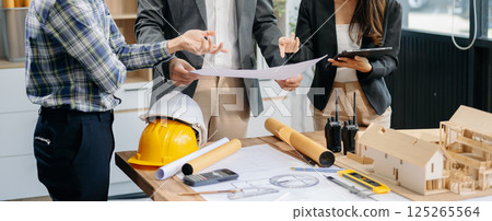 Engineer teams meeting working together wear worker helmets hardhat with on architectural project site and making model house. Asian industry professional team 125265564