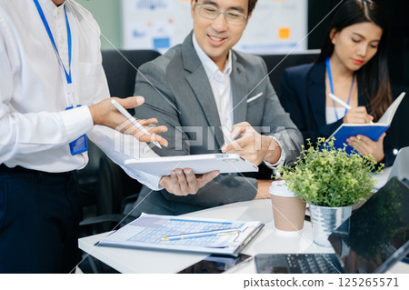 Happy Asian businesspeople while collaborating on a new project. using a laptop and tablet Happy Asian businesspeople while collaborating on a new project. using a laptop and tablet 125265571