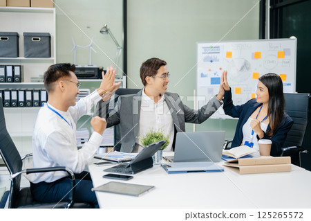 Happy Asian businesspeople while collaborating on a new project.  using a laptop and tablet 125265572