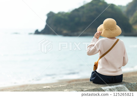 A middle-aged woman strolling along the seaside in spring 125265821