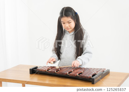 Elementary school girl practicing xylophone Elementary school girl practicing xylophone 125265837