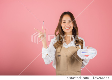 Asian beautiful young woman artist holding brush and paint palette, Happy female painting using paintbrush and palette with colors, studio shot isolated on pink background, Paintings and art equipment Asian beautiful young woman artist holding brush and paint palette, Happy female painting using paintbrush and palette with colors, studio shot isolated on pink background, Paintings and art equipment 125266363