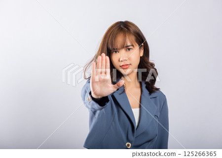 Asian portrait beautiful cute young businesswoman teen smiling doing show stop sign gesture with palm of hand but happy face studio shot isolated on white background, female doubt with copy space Asian portrait beautiful cute young businesswoman teen smiling doing show stop sign gesture with palm of hand but happy face studio shot isolated on white background, female doubt with copy space 125266365