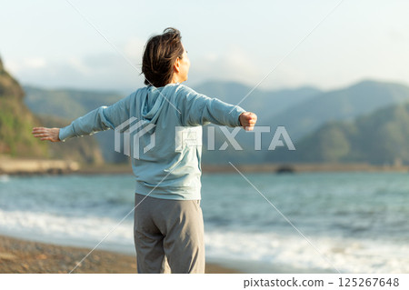 晚上在海灘上做伸展運動的中年婦女 125267648