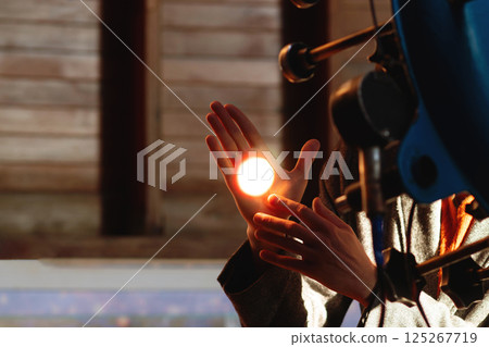 Bright circle of telescope light glows on man's hand. 125267719