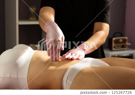 Spa therapist performs abdominal massage with circular hand movements. Spa therapist performs abdominal massage with circular hand movements. 125267726