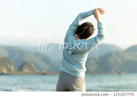 晚上在海灘上做伸展運動的中年婦女 125267774