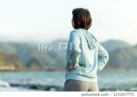 晚上在海灘上做伸展運動的中年婦女 125267775