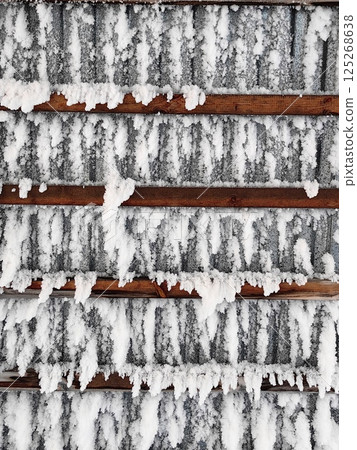 winter snow accumulation on roof with wooden slats creating textured display in quiet neighborhood. 125268638