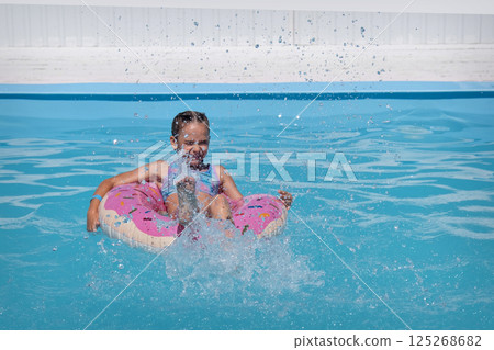 A girl in a swimsuit swims in a perfume circle in the pool, on the beach. Sunset on the shore of the blue sea, a child in a swimsuit. Childhood happiness, beach, vacation, sunscreen, warm weather A girl in a swimsuit swims in a perfume circle in the pool, on the beach. Sunset on the shore of the blue sea, a child in a swimsuit. Childhood happiness, beach, vacation, sunscreen, warm weather 125268682