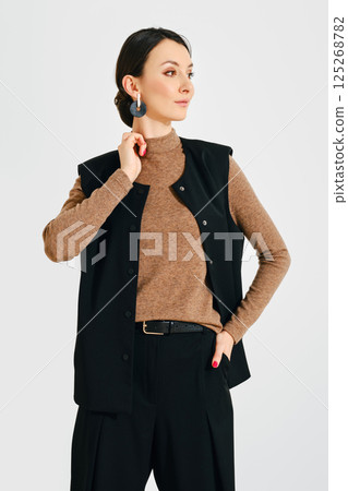 Model showcases stylish black vest with brown turtleneck in a clean studio setting during daylight Model showcases stylish black vest with brown turtleneck in a clean studio setting during daylight 125268782