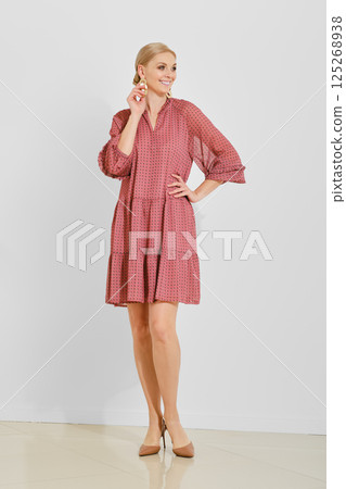 Model poses in stylish pink dress showcasing elegance and modern fashion trends 125268938