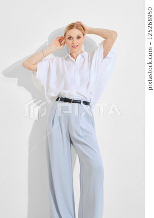 Model poses elegantly in light clothing against a minimalist backdrop during a fashion shoot Model poses elegantly in light clothing against a minimalist backdrop during a fashion shoot 125268950