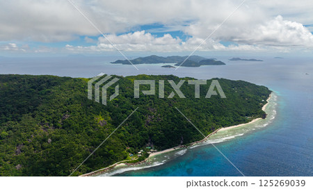 A lush green island surrounded by bright blue seas and a clear sky above. Felicite, Seychelles. 125269039