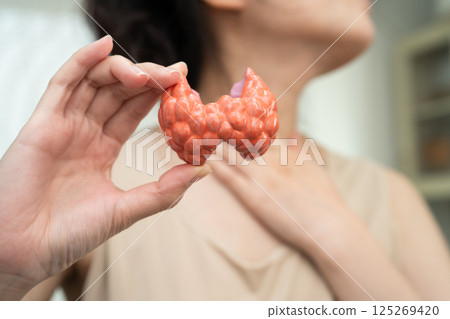 Hyperthyroidism, Overactive Thyroid, Thyroid Lymphoma, Asian woman with thyroid gland human anatomy model. Hyperthyroidism, Overactive Thyroid, Thyroid Lymphoma, Asian woman with thyroid gland human anatomy model. 125269420