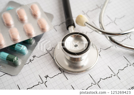 Stethoscope on electrocardiogram ECG with capsule drug, heart wave, heart attack, cardiogram report. 125269423