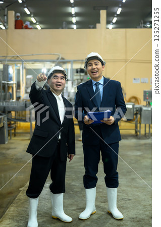Two factory executives discussing operations inside a food manufacturing facility 125271255
