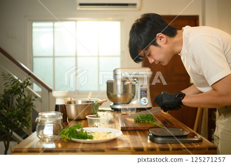 Close up of man chopping fresh herbs, preparing ingredients in a home kitchen 125271257