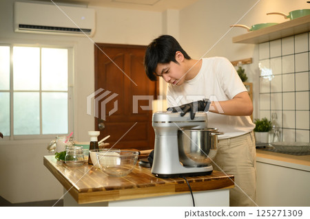 Young asian man preparing whipped cream with a stand mixer in home kitchen 125271309