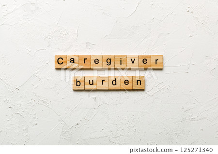 Caregiver burden word written on wood block. Caregiver burden text on cement table for your desing, concept 125271340