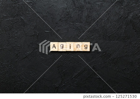 Aging word written on wood block. Aging text on cement table for your desing, concept Aging word written on wood block. Aging text on cement table for your desing, concept 125271530