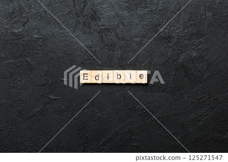 EDIBLE word written on wood block. EDIBLE text on cement table for your desing, concept 125271547