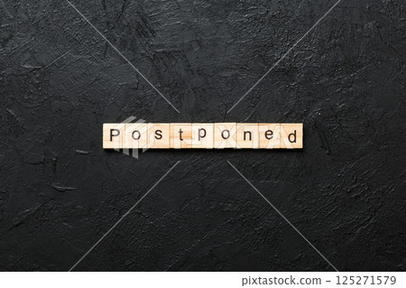 Postponed word written on wood block. Postponed text on cement table for your desing, concept 125271579