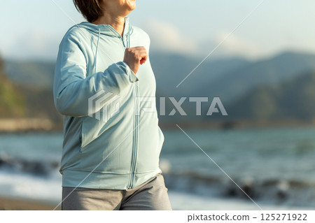 傍晚在沙灘上跑步的中年婦女 傍晚在沙灘上跑步的中年婦女 125271922