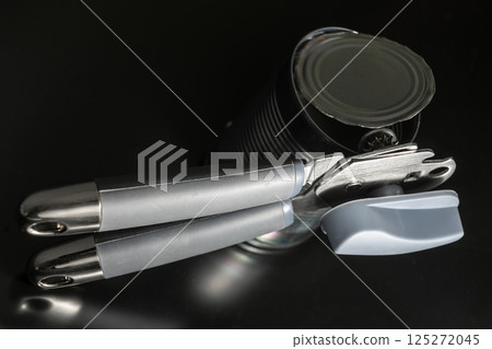 Metal Can Opener with Opened Tin on Dark Background Metal Can Opener with Opened Tin on Dark Background 125272045