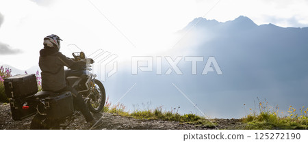 Motorcycle rider riding in Italian Alps during sunrise, dramatic sky. Travel and freedom, outdoor activities Motorcycle rider riding in Italian Alps during sunrise, dramatic sky. Travel and freedom, outdoor activities 125272190