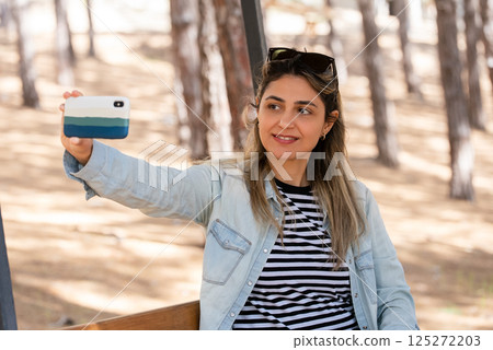 Portrait of smiling woman taking selfie with smartphone Portrait of smiling woman taking selfie with smartphone 125272203