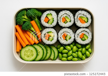 Vegan sushi rolls with cucumber and carrot served with fresh vegetables in bento lunch box on white background, top view 125272443