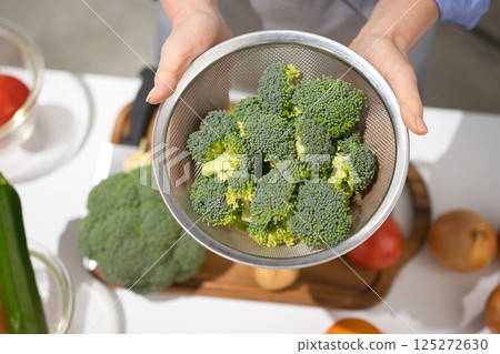 Middle-aged woman's hand holding fresh broccoli 125272630