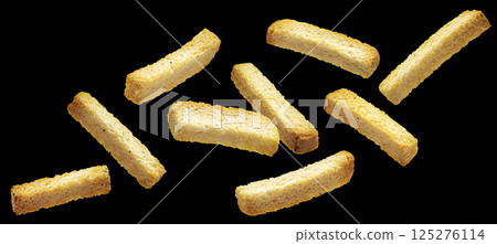 Crispy white bread rusks falling on black background, crunchy snack sticks Crispy white bread rusks falling on black background, crunchy snack sticks 125276114