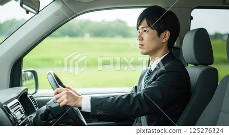 Asian man in a suit driving a car 125276324