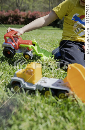 A child plays with toy cars on the lawn in the sunny day 125277665