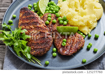 grilled beef cutlets with potato mash, green peas 125277760